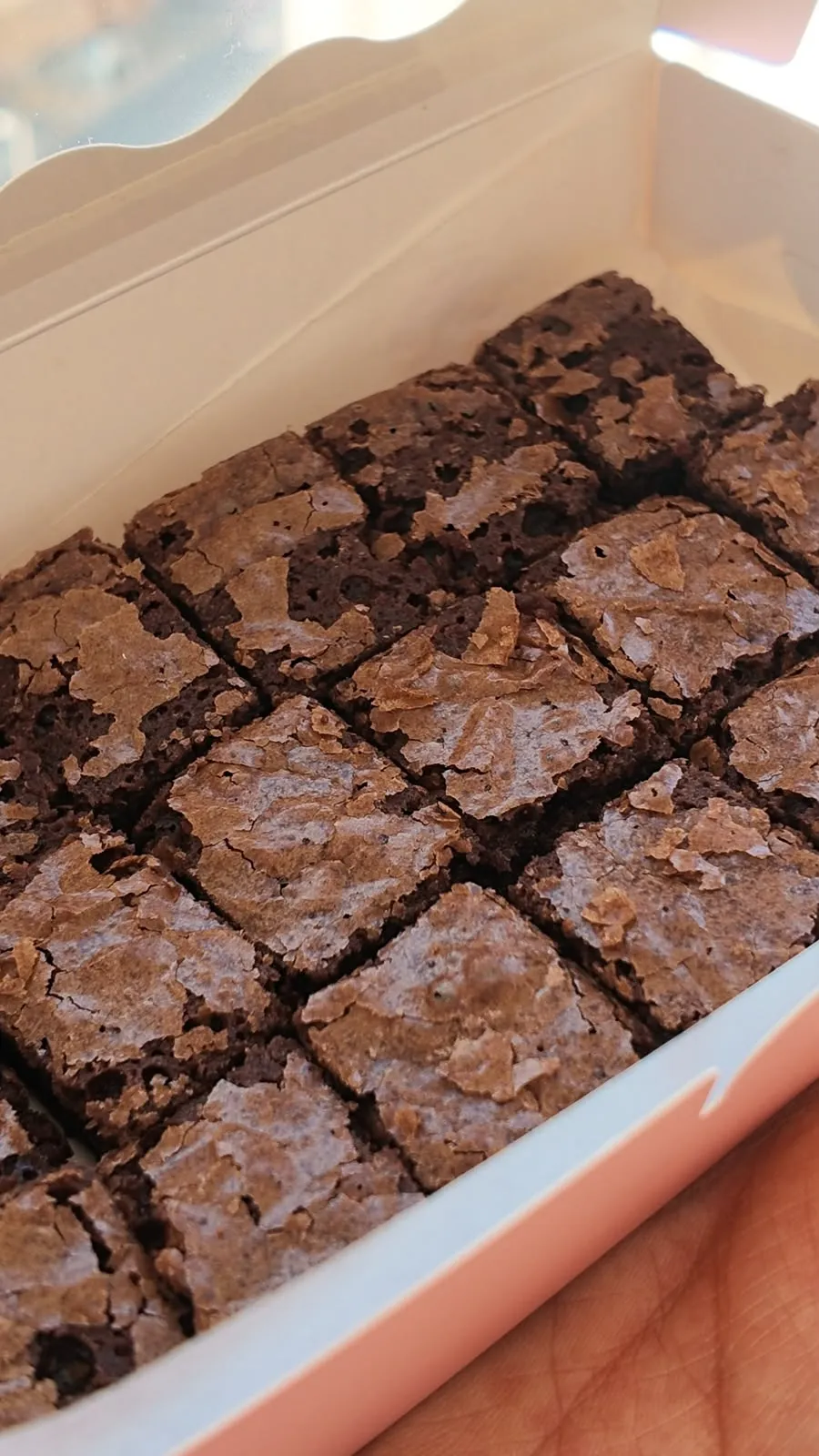 A tray of fudgy brownies with crackly tops, cut into squares